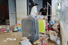 Người dân xã Ninh Phước (Khánh Hòa) dọn dẹp nhà cửa sau mưa lũ. (Ảnh: Nguyễn Thành/TTXVN)