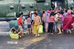 Người dân xã Phong Liên 1 và Phong Liên 2 nhận hàng cứu trợ từ trực thăng của Trung đoàn Không quân 917. (Ảnh: TTXVN phát)