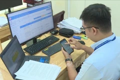 Công chức cấp xã tại Thành phố Hồ Chí Minh đã hoàn toàn quen với việc tiếp nhận và xử lý công việc trên laptop, điện thoại hoặc máy tính bảng. (Ảnh: TTXVN phát)