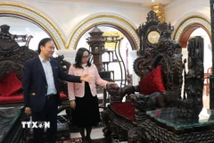 Đại diện Công ty Đồ gỗ mỹ nghệ Nam Thắng, phường Đồng Nguyên, tỉnh Bắc Ninh (bên trái) giới thiệu các mặt hàng gỗ của gia đình. (Ảnh: Thanh Thương/TTXVN)