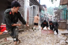 Các chiến sỹ đồn biên phòng Cửa khẩu Quốc tế Thanh Thủy (Tuyên Quang) giúp người dân dọn vệ sinh sau lũ. (Ảnh: Đức Thọ/TTXVN)