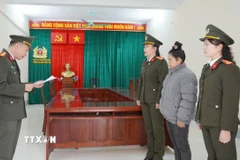 Cán bộ cơ quan An ninh điều tra công an tỉnh Điện Biên đọc Quyết định khởi tố bị can và Lệnh cấm đi khỏi nơi cư trú đối với Vì Thị Tiện. (Ảnh: TTXVN phát)