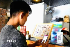 Khách hàng sử dụng phương thức giao dịch thanh toán trực tuyến. (Ảnh: TTXVN phát)