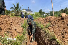 Các lực lượng khẩn trương tìm kiếm hài cốt liệt sỹ tại nghĩa trang liệt sỹ tạm ấp Tân Hòa. (Ảnh: Huỳnh Phúc Hậu/TTXVN)