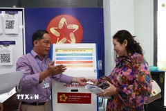 Hỗ trợ người dân đăng ký dịch vụ và lấy số thứ tự tại Văn phòng Đăng ký đất đai Thành phố Hồ Chí Minh. (Ảnh: Hồng Đạt/TTXVN)