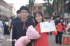 Nguyễn Khắc Công chụp ảnh cùng mẹ trong Lễ tuyên dương học sinh giỏi tại trường. (Ảnh: TTXVN phát)