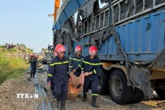 Lực lượng chức năng đưa thi thể nạn nhân ra ngoài. (Ảnh: TTXVN phát)