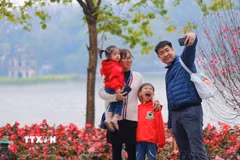 Một gia đình cùng nhau ghi lại khoảnh khắc của mùa Xuân bên hồ Gươm. (Ảnh: Thanh Tùng/TTXVN)