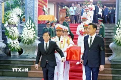 Đại biểu thực hiện nghi thức di quan để an táng các hài cốt các liệt sỹ. (Ảnh: TTXVN phát)