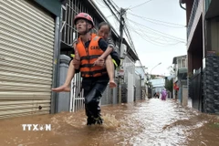 Một người lớn tuổi được lực lượng chức năng đưa ra ngoài an toàn khi nước dâng cao gây ngập nhà ở ven suối sau trận mưa lớn chiều 12/8. (Ảnh: Nguyễn Dũng/TTXVN)
