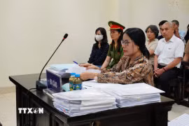 Bị cáo Nguyễn Thị Bình (đeo kính) và bị cáo Phạm Thị Minh Nguyệt (mặc áo sẫm màu, đeo khẩu trang trắng) tại phiên xử. (Ảnh: Kim Anh/TTXVN)