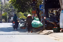 Người dân mặc đồ bảo hộ tránh nắng khi ra đường. (Ảnh: Tường Vi/TTXVN)