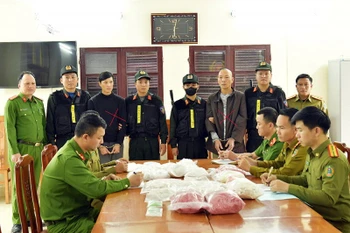 Đối tượng Phạm Lê Tuấn Anh (áo khoác đen) và Đinh Hồng Thuấn (áo dài xám) cùng tang vật bị thu giữ. (Nguồn: Công an cung cấp)