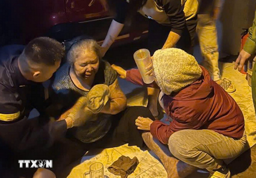 Lực lượng chức năng đã cứu được bà D.T.B. (sinh năm 1953) bị mắc kẹt trong đám cháy đưa ra vị trí an toàn. (Ảnh: TTXVN phát)