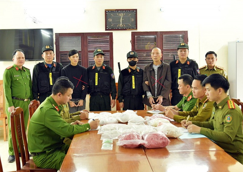 Đối tượng Phạm Lê Tuấn Anh (áo khoác đen) và Đinh Hồng Thuấn (áo dài xám) cùng tang vật bị thu giữ. (Nguồn: Công an cung cấp)