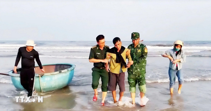Lực lượng của Trạm Kiểm soát Biên phòng Roòn hỗ trợ đưa ngư dân bị nạn lên bờ. (Ảnh: TTXVN phát)