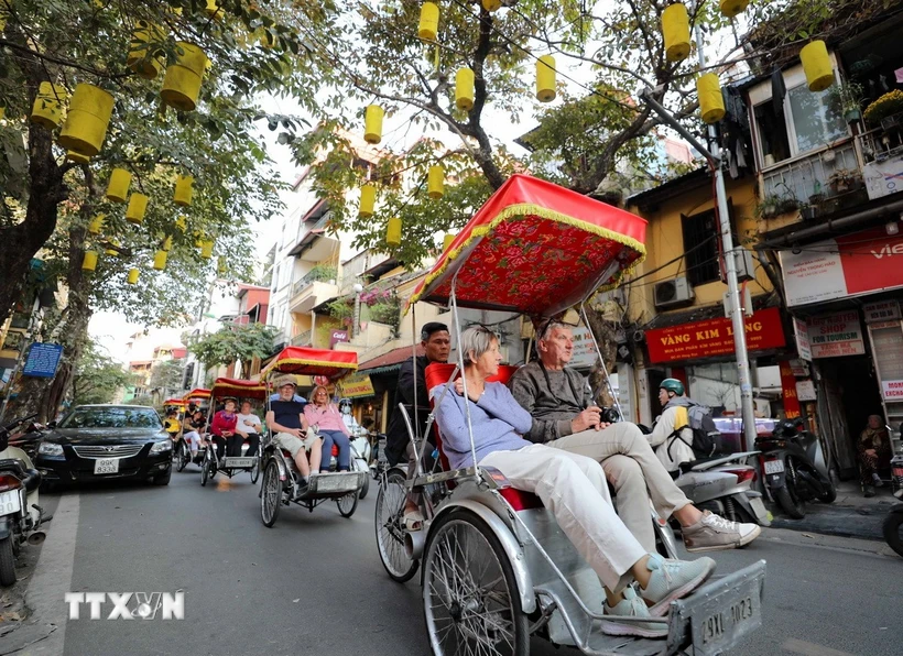 Du khách nước ngoài sử dụng xích lô thưởng ngoạn nét đẹp cổ kính của Phố cổ Hà Nội. (Ảnh: Thanh Tùng/TTXVN)