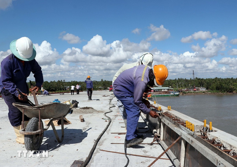 Giữa trưa nắng nóng như đổ lửa, các công nhân vẫn khẩn trương thi công các hạng mục phụ để sớm thông xe kỹ thuật cầu Đại Ngãi 2 dịp lễ 30/4. (Ảnh: Trung Hiếu/TTXVN)