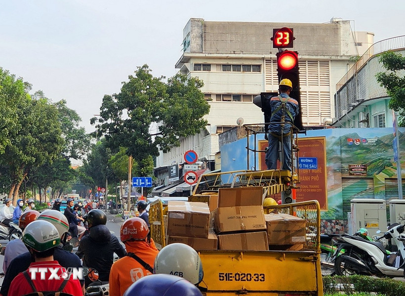 Công nhân gắn đèn tín hiệu cho phép rẽ phải khi đèn đỏ tại một số nút giao. (Ảnh: Tiến Lực/TTXVN)
