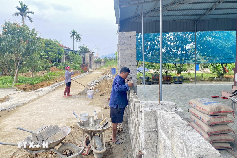 Người dân tại thôn Vĩnh Phúc, tỉnh Hà Tĩnh, xây dựng lại hàng rào sau khi hiến đất. (Ảnh: Hữu Quyết/TTXVN)
