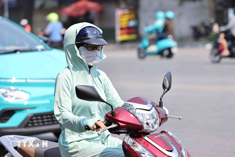 Mỗi khi phải ra đường, dù người lớn hay trẻ em đều dùng mọi biện pháp như khẩu trang hay áo chống nắng để chống lại cái nắng nóng gay gắt. (Ảnh: Minh Đức/TTXVN)