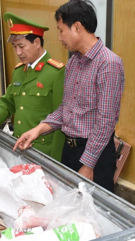 Đối tượng Hoàng Đình Đạt mặc áo kẻ sọc màu đỏ cùng tang vật vụ án. (Ảnh TTXVN phát)