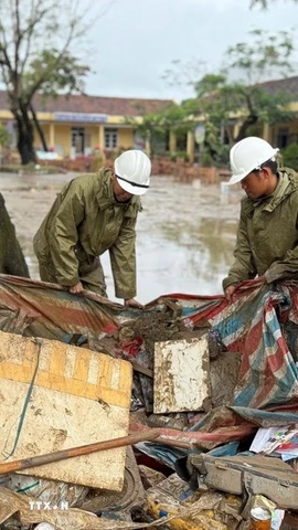Lực lượng Quân đội hỗ trợ người dân thu dọn rác và bùn đất sau khi nước rút. (Ảnh: Nguyên Dung/TTXVN)