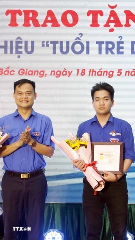 Phó Bí thư Thường trực Tỉnh đoàn Bắc Giang Bùi Văn Hoàng trao tặng Huy hiệu “Tuổi trẻ dũng cảm” cho 2 em là: Phạm Đình Tuấn và Phạm Hoàng Long. (Ảnh: Đồng Thúy/TTXVN)