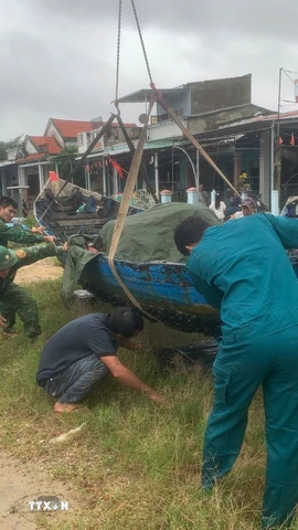Các lực lượng hỗ trợ giúp đỡ người dân chằng chống, bảo vệ phương tiện trước khi bão vào đất liền. (Ảnh: Đoàn Hữu Trung/TTXVN)