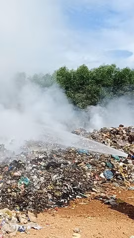 Các lực lượng chức năng đang tập trung nhân lực và phương tiện dập lửa tại Khu xử lý rác Trường Thủy. (Ảnh: TTXVN phát)