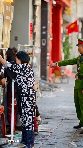 Lực lượng chức năng đi vận động hộ kinh doanh không lấn chiếm vỉa hè tại phố Phan Chu Trinh, phường Cửa Nam. (Ảnh: Quốc Lũy/TTXVN)
