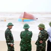Lên phương án trục vớt tàu cá bị đánh chìm và dạt vào tại khu vực biển xã Bắc Trạch. (Ảnh: Tá Chuyên/TTXVN)
