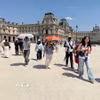 Nhiều du khách mang theo ô và nước uống khi tham quan bảo tàng Louvre trong đợt nắng nóng tại Paris, Pháp. (Ảnh: Hữu Chiến/TTXVN)