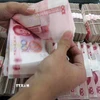 Kiểm tiền mệnh giá 100 nhân dân tệ tại một ngân hàng ở Bắc Kinh, Trung Quốc. (Ảnh: Getty Images/TTXVN)