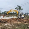Xe múc được huy động khắc phục đoạn đê bị sạt lở do mưa lũ kéo dài. (Ảnh: Mai Trang/TTXVN)