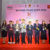 Tổng lãnh sự Việt Nam tại Khonkaen Đinh Hoàng Linh (thứ 4 từ bên phải sang) chụp ảnh cùng đại diện doanh nghiệp, khách tham quan tại Hội chợ Beyond Food Expo 2026. (Ảnh: TTXVN phát)