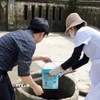 Cán bộ y tế hỗ trợ người dân xử lý nguồn nước sinh hoạt sau lũ. (Ảnh: TTXVN phát)