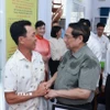 Thủ tướng Phạm Minh Chính thăm hỏi nhân dân thực hiện thủ tục hành chính tại Trung tâm phục vụ hành chính công phường Thới Sơn, tỉnh An Giang. (Ảnh: Dương Giang/TTXVN)