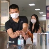 Hành khách sát khuẩn tay trước khi vào bến xe Giáp Bát. (Ảnh: Hoàng Hiếu/TTXVN)