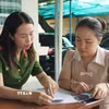 Cán bộ Công an hướng dẫn làm thủ tục cho người dân. (Ảnh: Trung Tuyến/TTXVN)