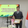 Bé Kim Trà My nhận Giấy khen từ lãnh đạo Đại sứ quán Việt Nam tại Nhật Bản. (Ảnh: Phạm Tuân/TTXVN)
