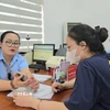 Công chức phường Mạo Khê, Quảng Ninh, hướng dẫn công dân nộp hồ sơ chứng thực lên Cổng dịch vụ công Quốc gia. (Ảnh: Thanh Vân/TTXVN)
