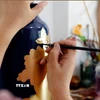 Vẽ hoa văn trên sản phẩm gốm sứ tại làng nghề Hạ Thái. (Ảnh: Trần Việt/TTXVN)