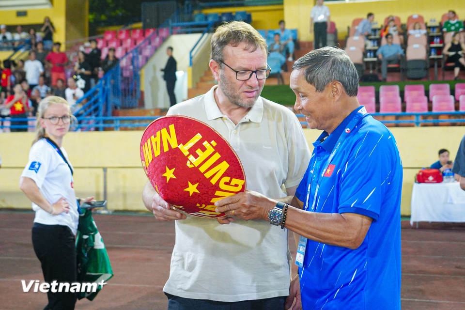 Huấn luyện viên trưởng Mai Đức Chung (áo xanh) gửi tặng người đồng nghiệp chiếc nón mang đậm bản sắc văn hóa Việt Nam trước trận đấu. (Ảnh: Việt Anh/Vietnam+)