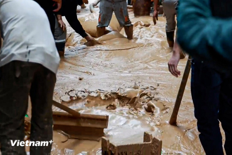 Tại thời điểm 9 giờ sáng, phần cống ở đoạn chính giữa ngõ tiếp tục phun trào hỗn hợp bùn đất với tốc độ rất nhanh, làm lan ra phần đường xung quanh mặc dù có đội nhà thầu đang nạo hút. (Ảnh: Minh Hiếu/Vietnam+)