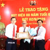 Đoàn công tác trao Huy hiệu 80 năm tuổi Đảng và hoa chúc mừng đảng viên Huỳnh Long Tòa, xã Cầu Ngang. (Ảnh: Thanh Hòa/TTXVN)
