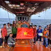 Lực lượng chấp pháp trên biển trao cờ tổ quốc và tuyên truyền IUU cho ngư dân đang đánh bắt trên biển. (Ảnh minh họa: Hoàng Nhị/TTXVN)