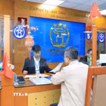 Cán bộ, công chức Trung tâm Phục vụ hành chính công thành phố Hà Nội-Chi nhánh số 3 hướng dẫn người dân hoàn thiện hồ sơ thủ tục hành chính. (Ảnh: TTXVN phát)
