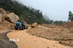 Lực lượng chức năng tỉnh Khánh Hòa huy động thiết bị cơ giới dọn dẹp đất đá bị sạt lở để tiếp cận hiện trường đưa nạn nhân ra ngoài. (Ảnh: Đặng Tuấn/TTXVN)