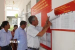 Người dân xem danh sách cử tri được niêm yết tại điểm bỏ phiếu. (Ảnh: Nhựt An/TTXVN)